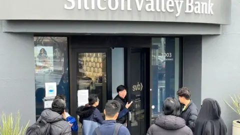 Getty Images A worker (C) tells people that the Silicon Valley Bank (SVB) headquarters is closed on March 10, 2023 in Santa Clara, California.