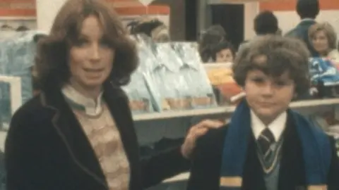 A BBC presenter with a schoolboy, discussing the cost of a school uniform