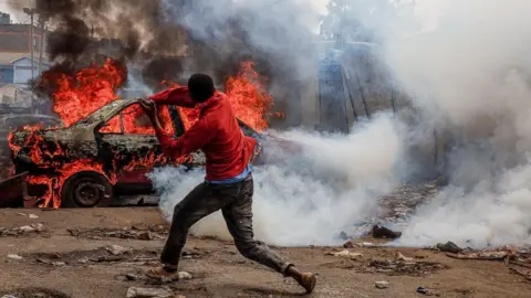 Getty Images A protester throws stones to the riot police during the Azimio la Umoja-One Kenya protest over high living cost on July 20, 2023 in Nairobi, Kenya