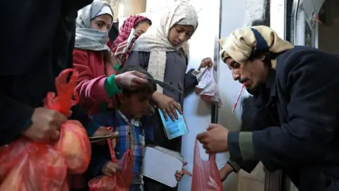 Reuters Children receive food aid at a charity kitchen in Sanaa, Yemen (14 January 2021)