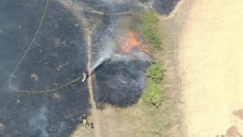 A firefighter using a hose to tackle the blaze