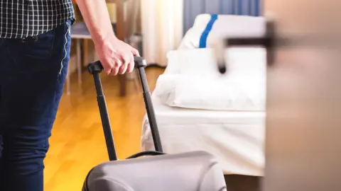 Getty Images Man entering hotel room with case