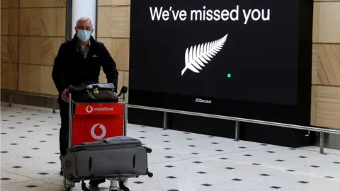 Reuters Man in front of a board at an airport saying "We've missed you"