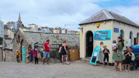 Getty Images People queuing at a fishmonger's in Tenby