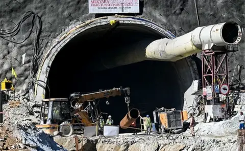 AFP rescue personnel manoeuvre a metal tube through an entrance of the under construction road tunnel, days after it collapsed in the Uttarkashi district of India's Uttarakhand state on November 21, 2023. Forty-one Indian workers trapped in a collapsed road tunnel for 10 days were seen alive on camera on November 21, for the first time, looking exhausted and anxious, as rescuers attempted to create new passageways to free them. (