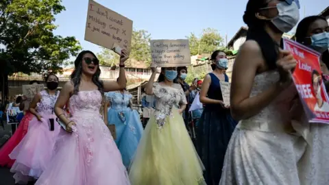 Getty Images Myanmar women in wedding gowns holds up placards during a demonstration