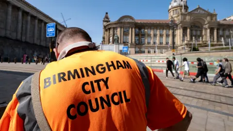 Getty Images Birmingham City Council refuse collector empties the bins opposite the Town Hall building in Victoria Square in the city centre on 5 September 2023 in Birmingham, United Kingdom