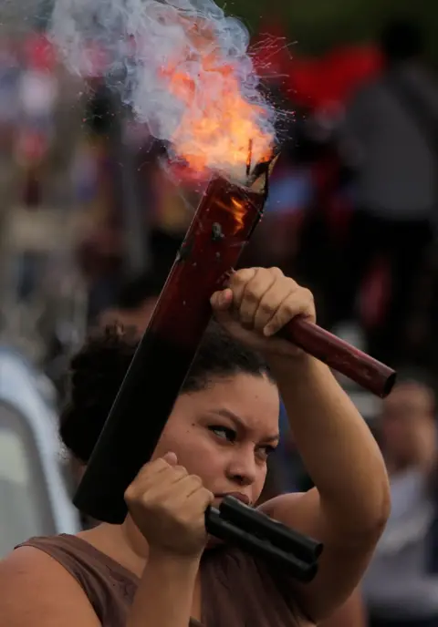 AFP A woman fires a home-made mortar vertically into the air during a pro-government rally