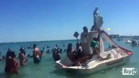 La Republicca A priest blesses bathers from the back of a seaside pedalo