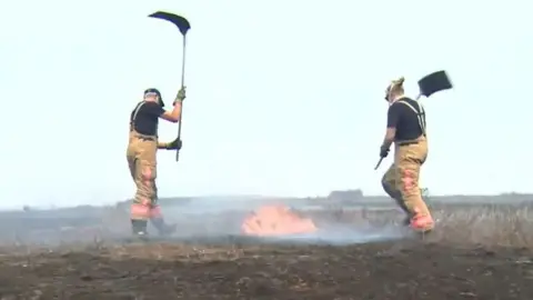 Firefighters beating flames on Saddleworth Moor