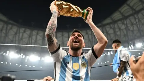 Messi celebrates with the World Cup trophy