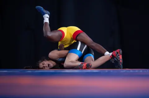EPA A handout photo made available by the OIS/IOC shows Zaineb Sghaier of Tunisia (blue) in action against Natacha Veronique Nabaina of Cameroon (yellow) in the Wrestling Women"s Freestyle 65kg Group B at the Asia Pavilion, Youth Olympic Park during The Youth Olympic Games, Buenos Aires, Argentina, 13 October 2018.