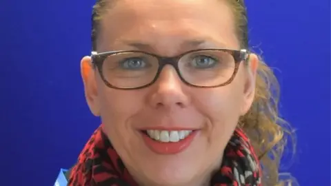 Kettering General Hospital Woman with long hair tied back, wearing glasses