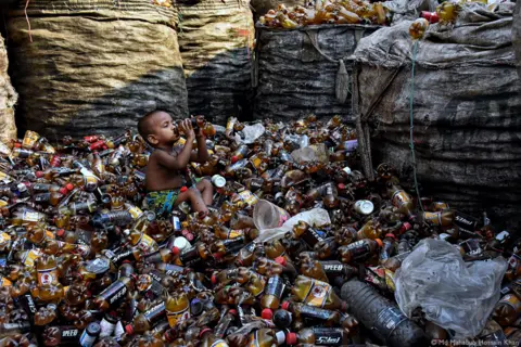 Md Mahabub Hossain Khan Child surrounded by plastic bottles