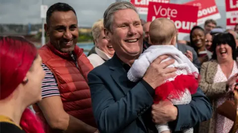 Getty Images Sir Keir Starmer holds a baby as he celebrates the local election results on Chatham Pier in Kent