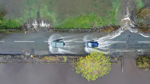 Getty Images Cars driving on a flooded road as the River Conwy bursts its banks in Llanrwst last October