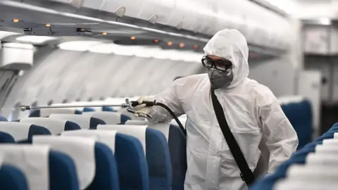 AFP Man spraying plane with disinfectant