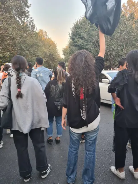 Social media A woman with her hair loose holding a scarf above her head