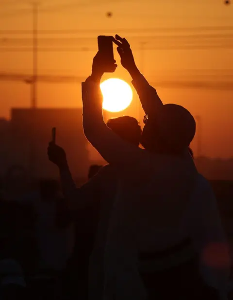 Ali Haider / EPA-EFE Muslims take photos during the Eid Al-Fitr prayer