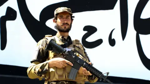 EPA Taliban stand guard outside the building of former US embassy as the wall painted with text in Arabic "There is not God but Allah, Muhammad is the messenger of Allah" in Kabul