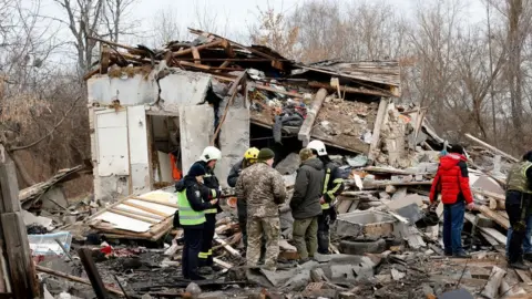 Getty Images Rescue teams examine a damaged home in the Kyiv region