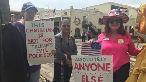 Three women protest Trump nearby