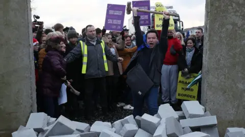 PA A man cheers after knocking dock a mock border wall at a Brexit protest near Newry