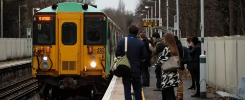 Getty Images Commuters on a platform as a train arrives