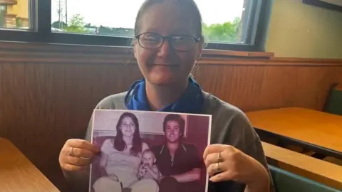 Handout Holly Crouse holds a photo of her murdered parents