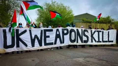 BBC Protesters waving Palestinian flags and holding a banner saying UK weapons kill