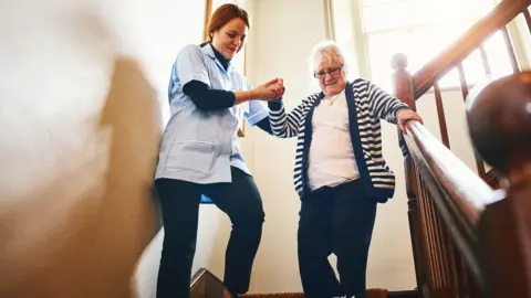 Dean Mitchell/Getty Images Carer with elderly person