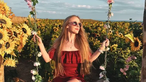 @wales_on_my_doorstep / Kimberley Lane Stacey on a swing made of sunflowers