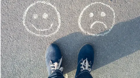 Getty Images Feet standing by chalk faces - one smiling, one unhappy