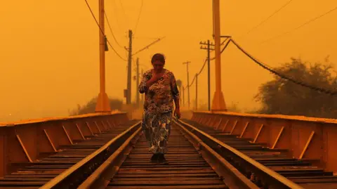 AFP A woman walks on a bridge during the fires in Renaico, Araucania region, Chile on February 4, 2023