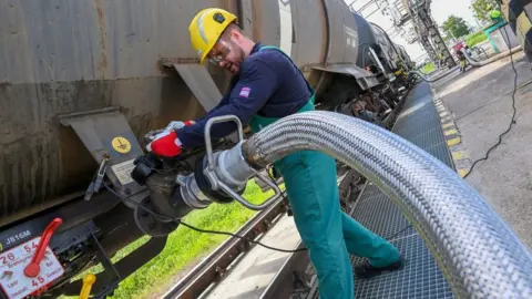 Getty Images A worker prepares to receive liquid additive for petroleum refining from a tanker train at the Duna (Danube) Refinery of Hungarian MOL Company located near the town of Szazhalombatta