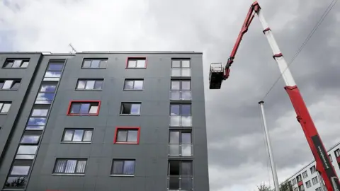 Getty Images Cladding tiles being removed from a block in Salford for testing