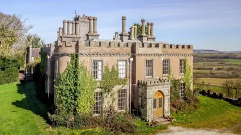 Knight Frank A tudor style manor house with ivy growing up the front