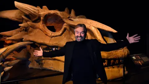 Reuters Actor Ian Beattie, who played Meryn Trant, with a dragon skull at the Game of Thrones Studio Tour