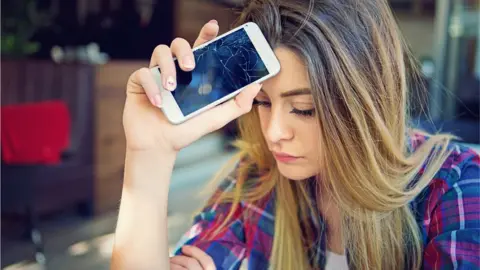 Getty Images young woman with cracked mobile phone