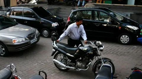 Getty Images A man pushes his motorbike out of a car dealership, on April 14, 2008 in Bangalore, India.