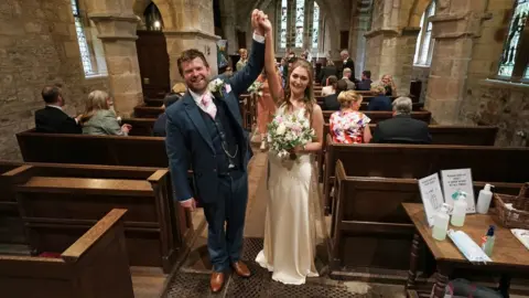 PA Media James Bone and Lucy Johnston celebrate in the church