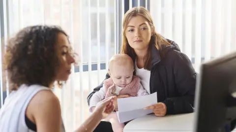 Getty Images Woman and baby with a benefits officer