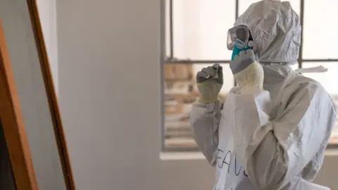 Getty Images A health worker puts on PPE at the Ebola Treatment Centre in Mubende Regional Referral Hospital on 10 October, 2022