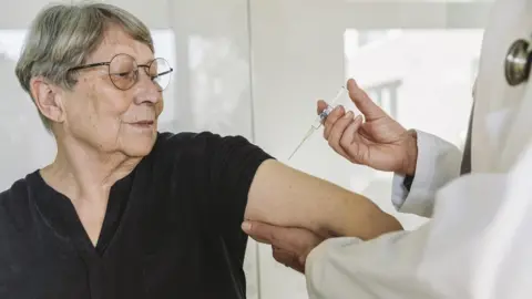 Getty Images Stock photo of a woman being injected by a doctor