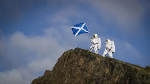 Actors Joy Maria Onotu (left) and Sarah Miele, stars of the Edinburgh Fringe show 'Valentina's Galaxy' take their first steps on what looks like a new planet but is in fact the Salisbury Crags in Holyrood Park above the city of Edinburgh, 15 Auguest 2019.