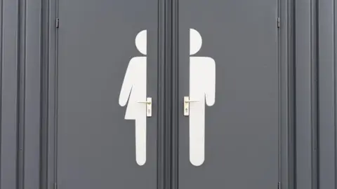 Getty Images Door with half a woman's toilet symbol beside half a men's toilet symbol