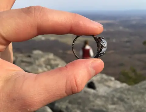 Lyd Fama A close up of the ring, with Meg in the far distance seen through the middle of it