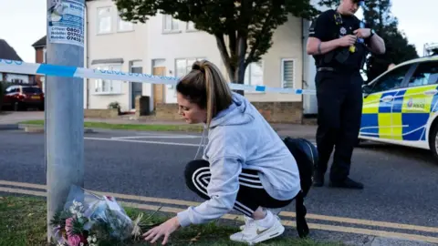 Getty Images A member of the public leaves flowers at the scene.