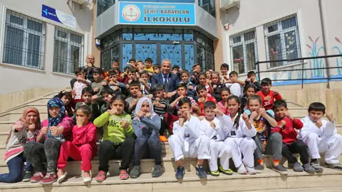 Sehit Karayilan primary headmaster Ali Riza Gundemir with Turkish and Syrian students