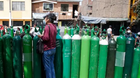 Reuters A woman stands behind empty oxygen tanks waiting to be recharged at a private supplier